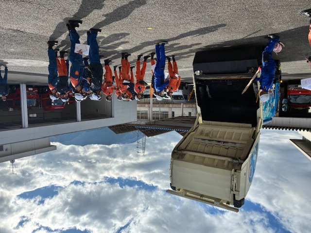 ゴミ収集車後方のゲートを開け、内部の構造について説明を受けている様子。