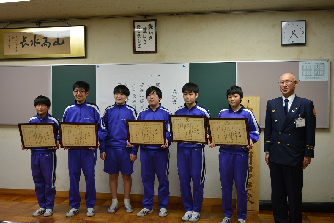 感謝状を持って記念写真をとる中学生と消防長