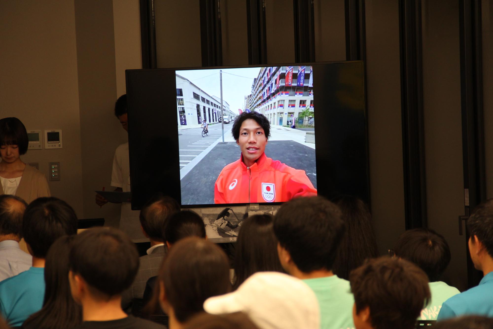 田中選手から届いた動画を見ている市民