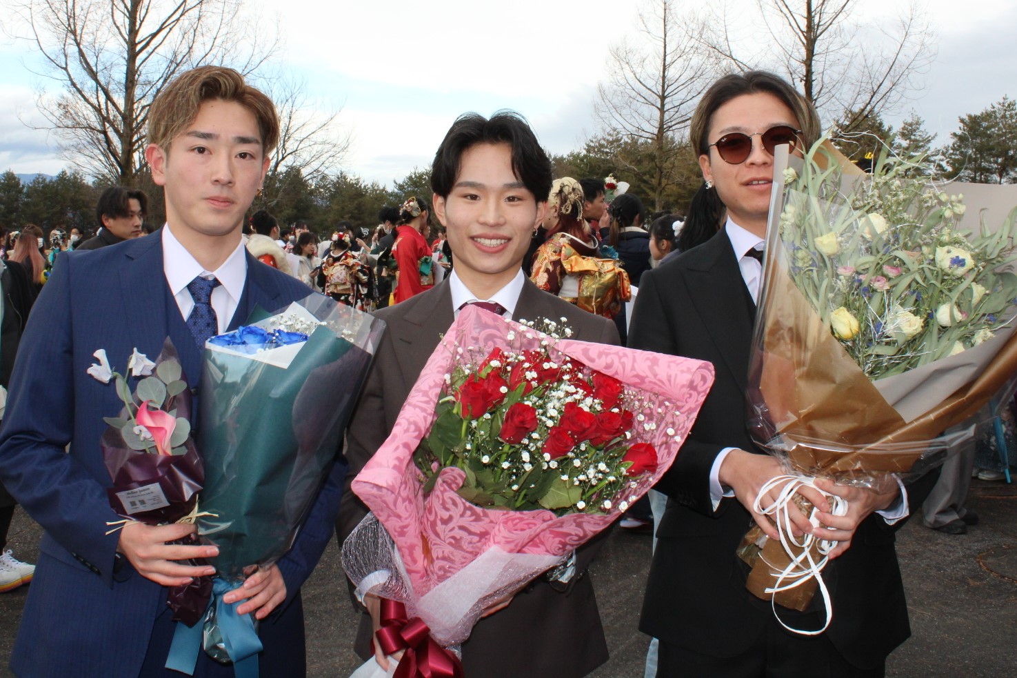 屋外で花束を持って記念撮影をする二十歳の皆さん