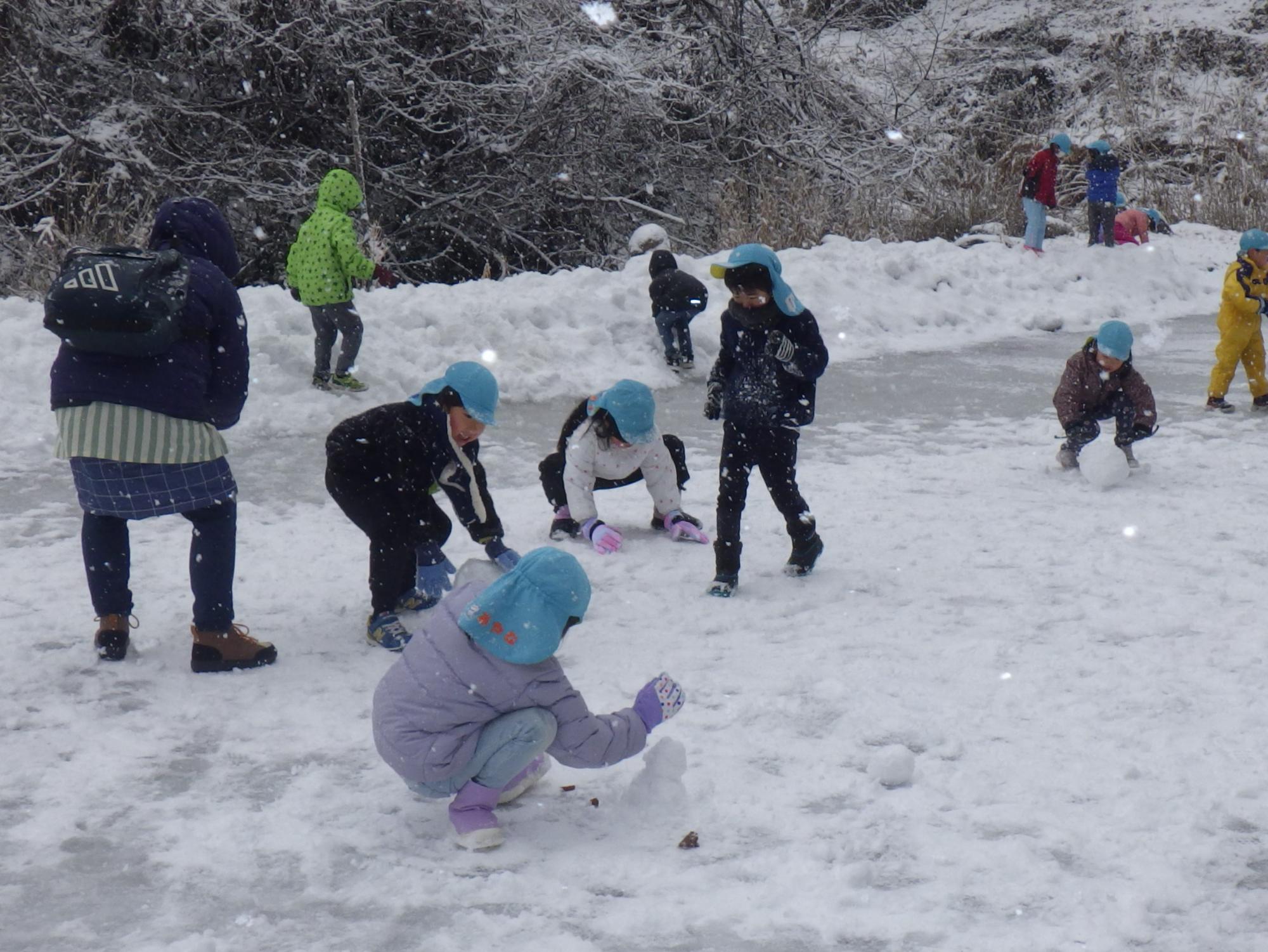 天然のスケート場で雪遊びをする園児たち