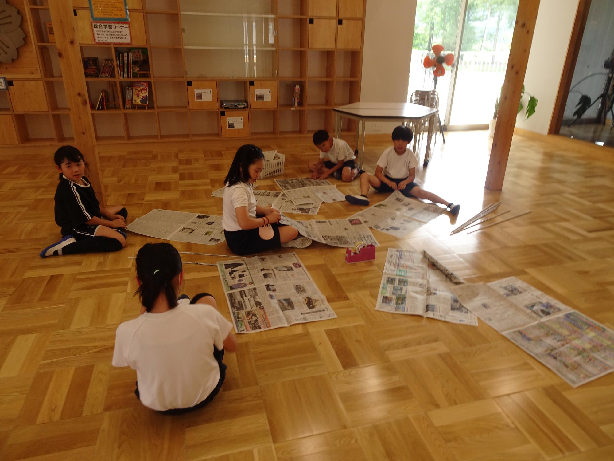 新聞をひろげて作業する子ども