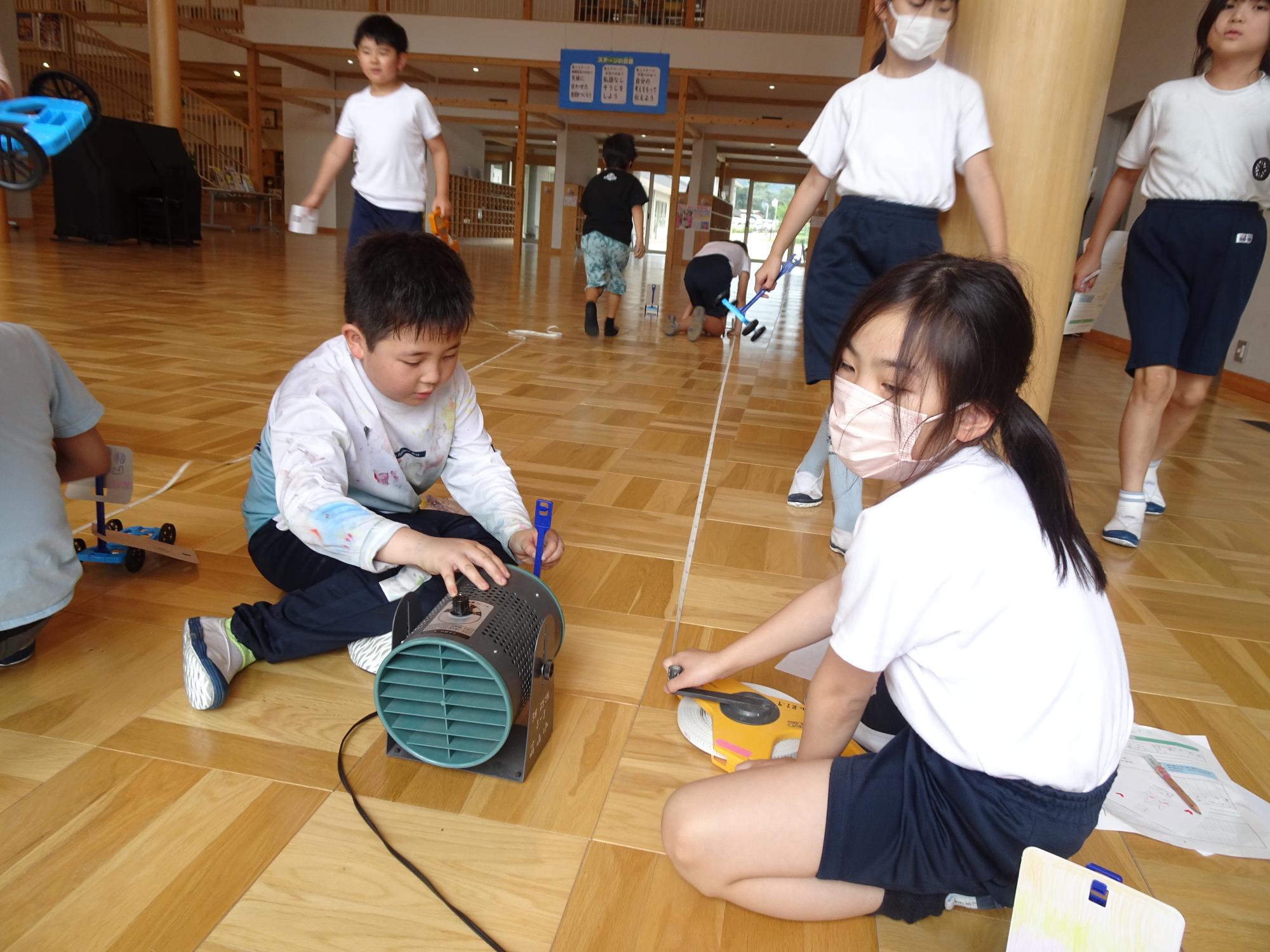 風で動く車の走行距離を測る子ども