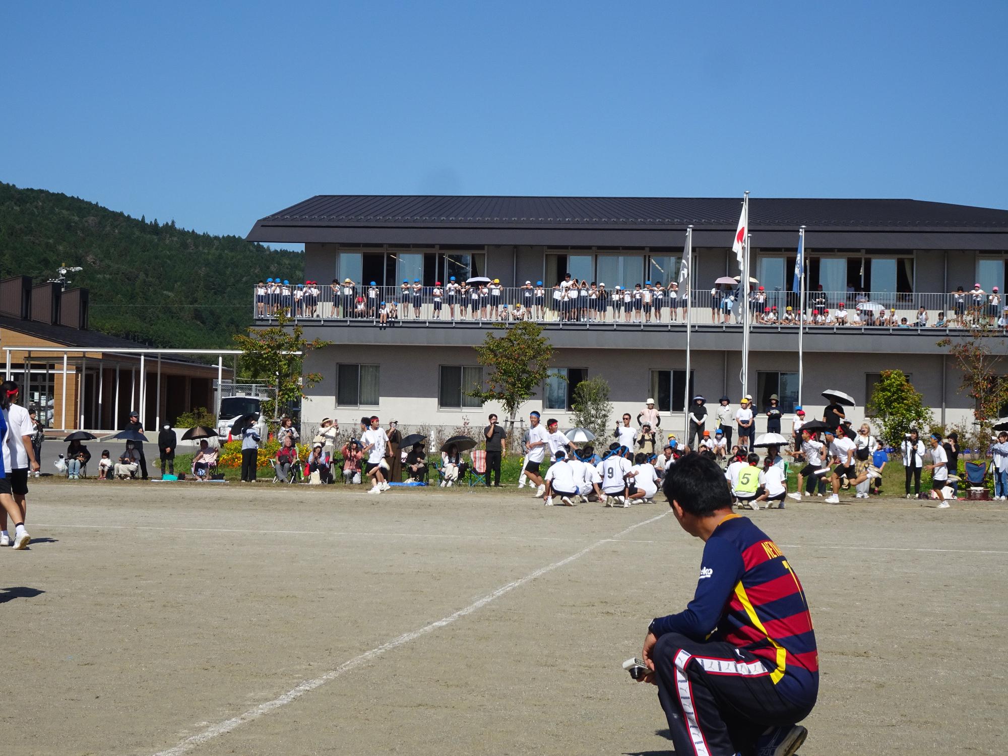 中学生のリレーを見る小学生