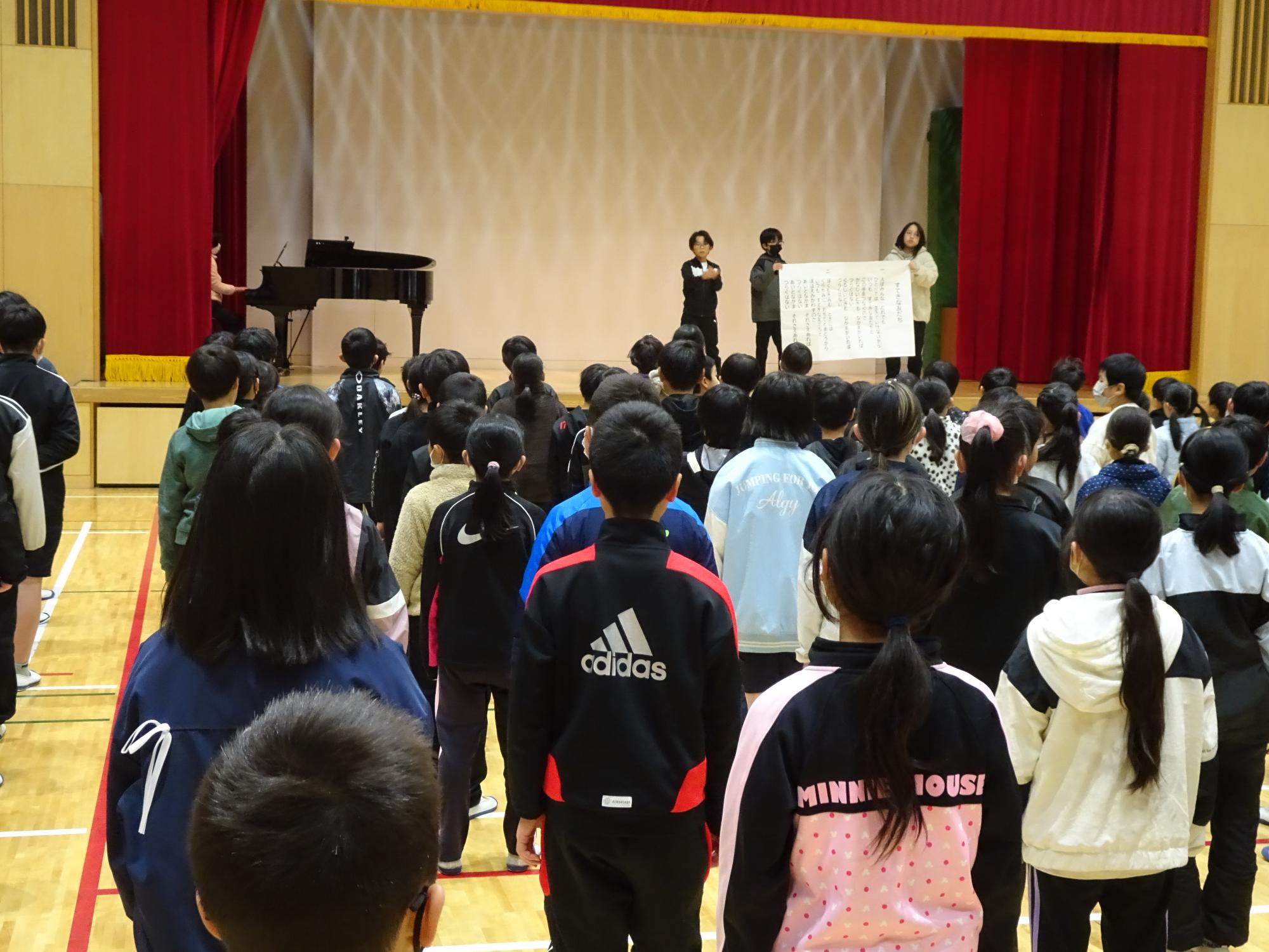 集会で歌を歌う児童