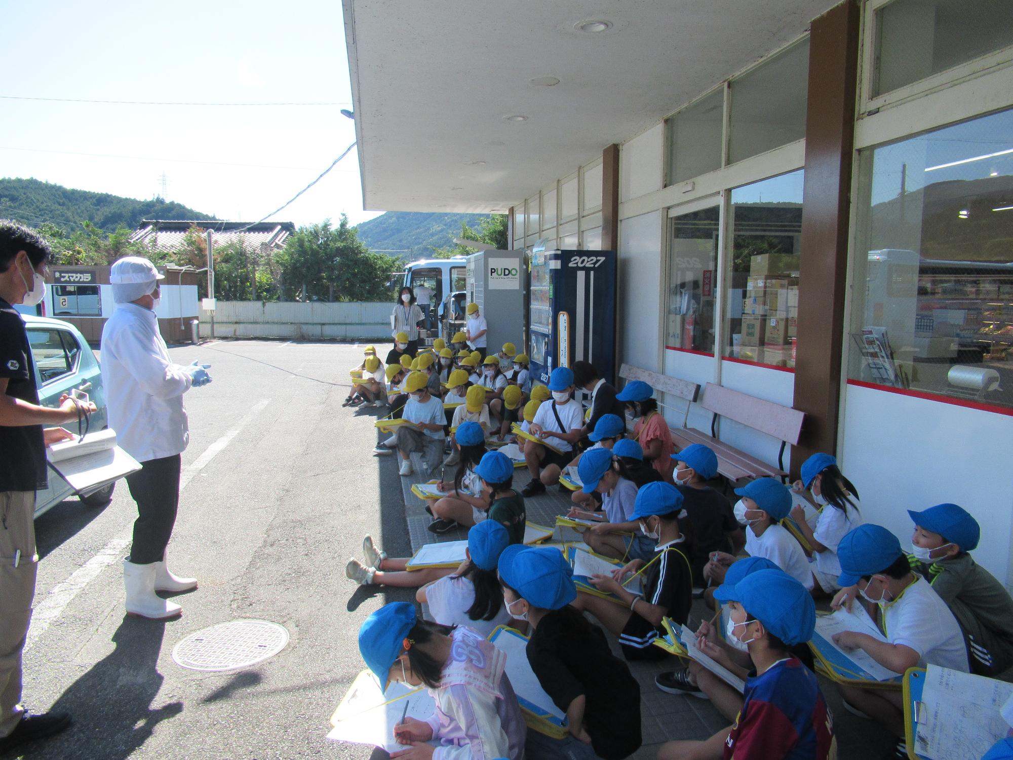 スーパーの人の話を聞く子ども