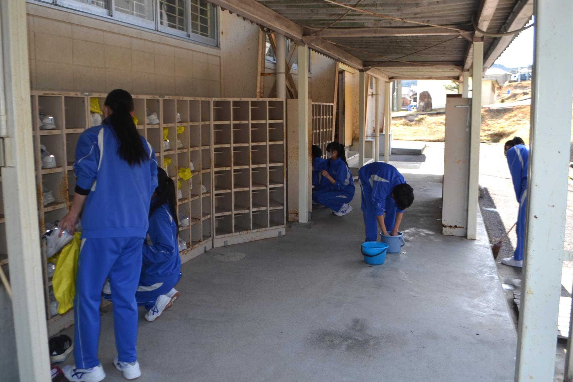 体育館前の下駄箱を掃除する生徒