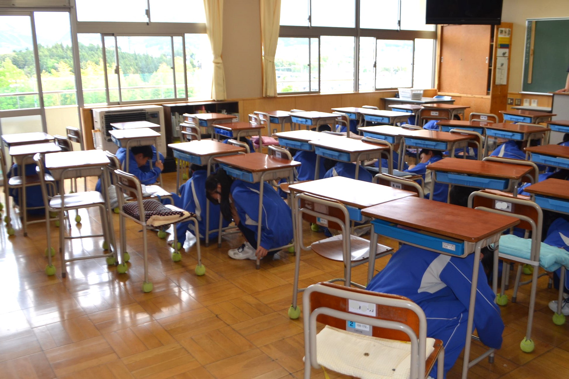 机の下で安全を確保する生徒の様子