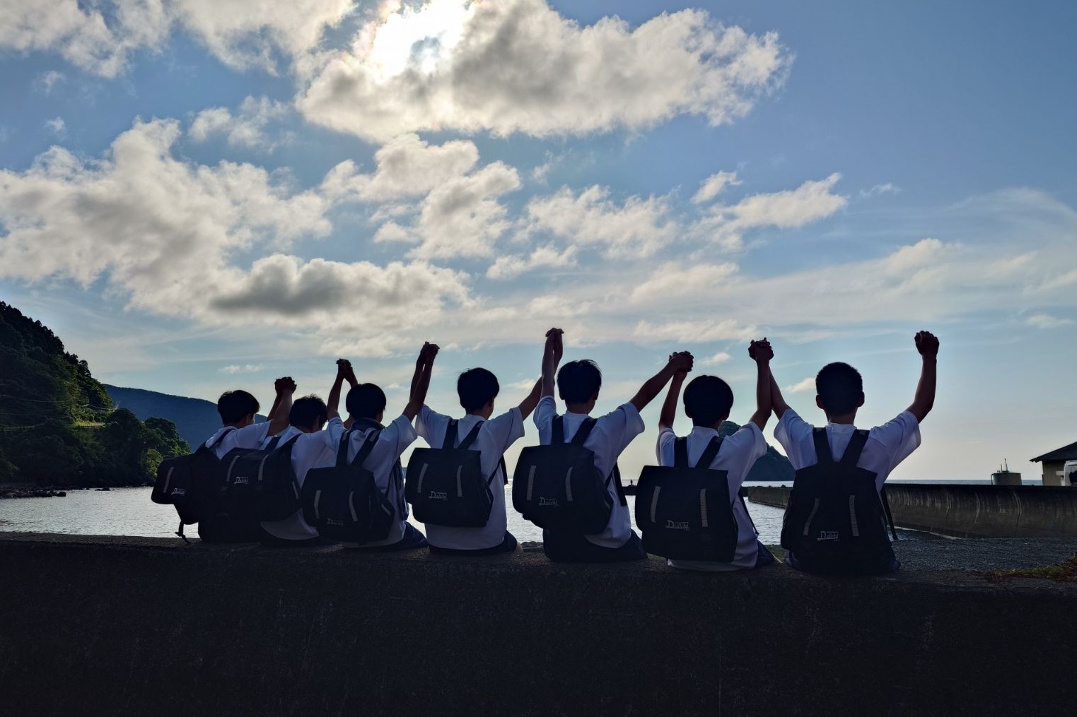 海に向かって手をつなぐ生徒