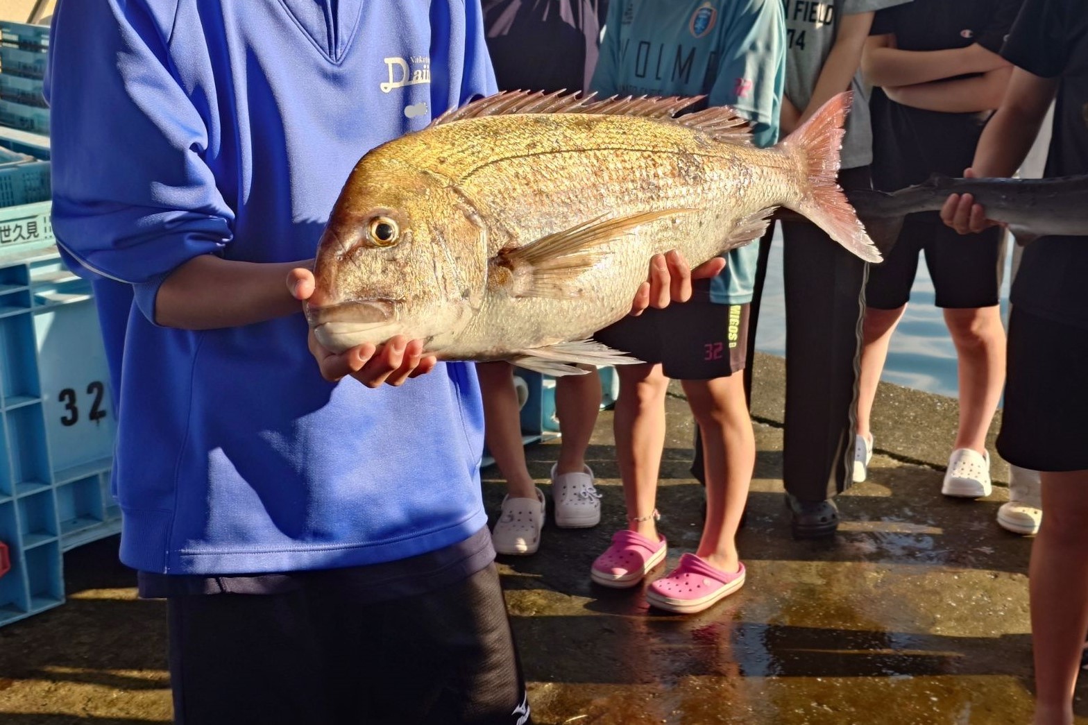 水揚げされた魚を抱える生徒