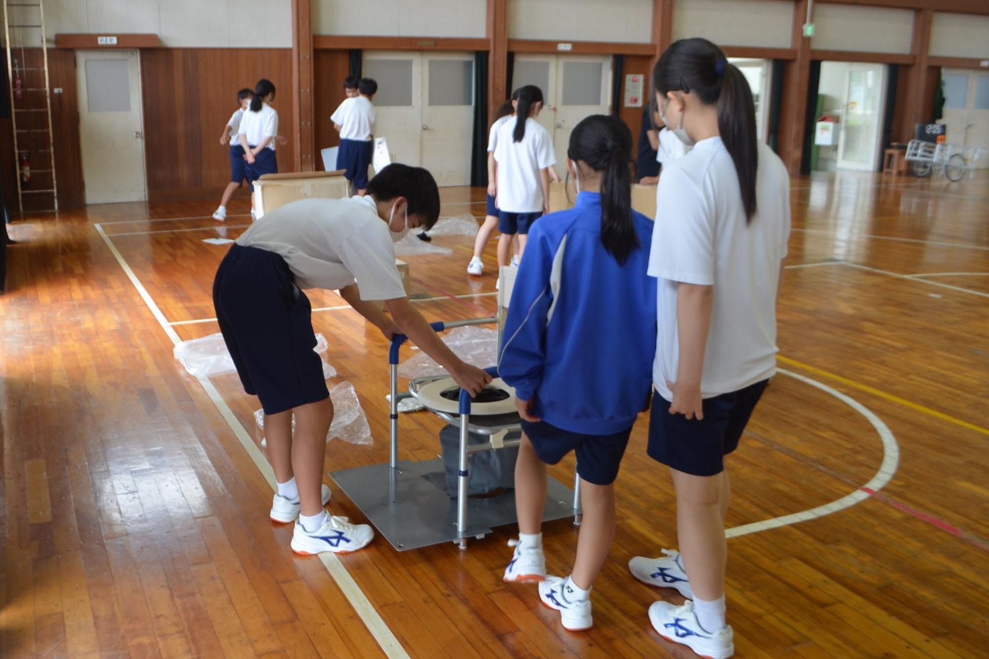 簡易トイレを組み立てる生徒