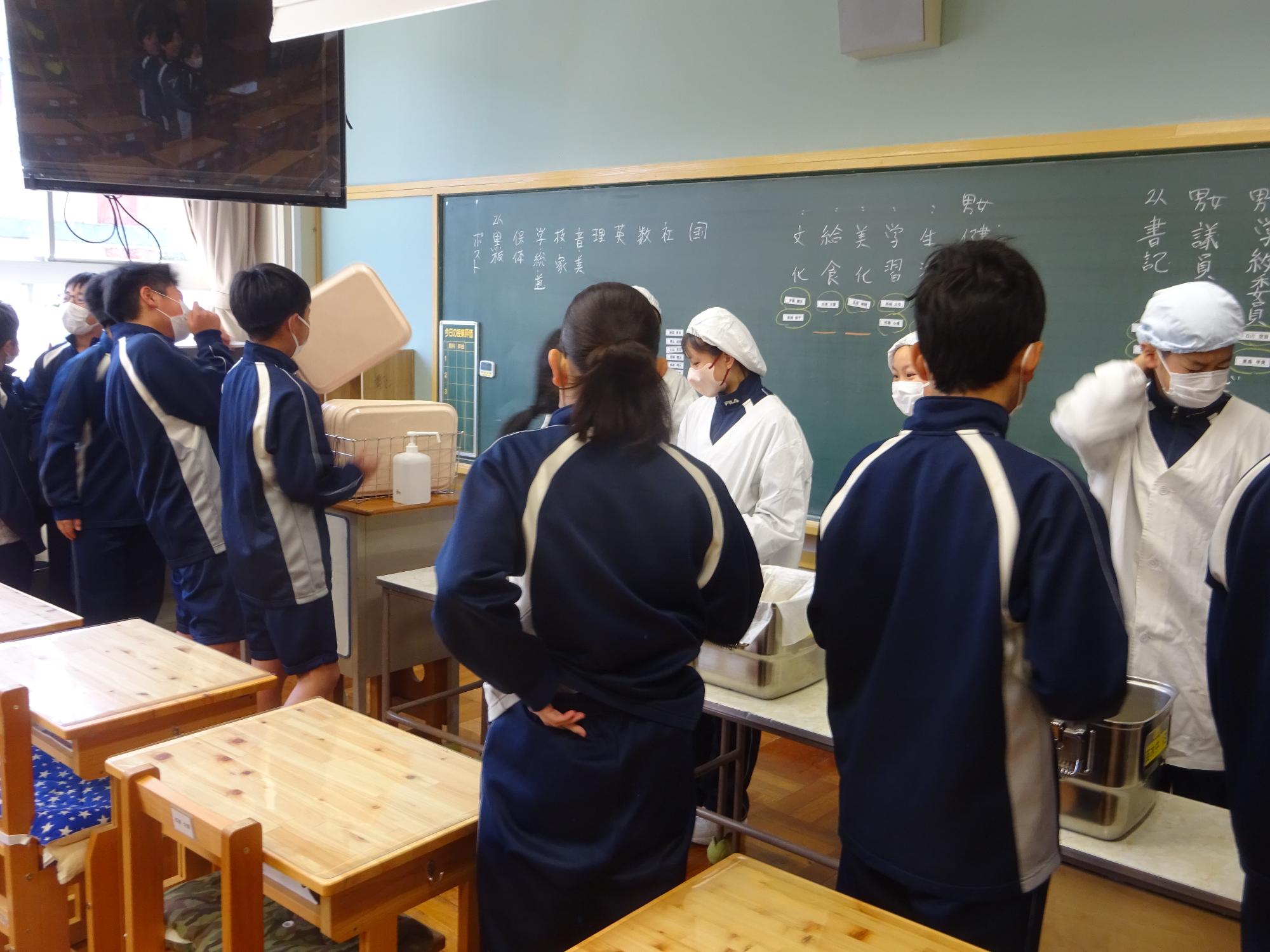 三年生に指示されながら配膳する一年生