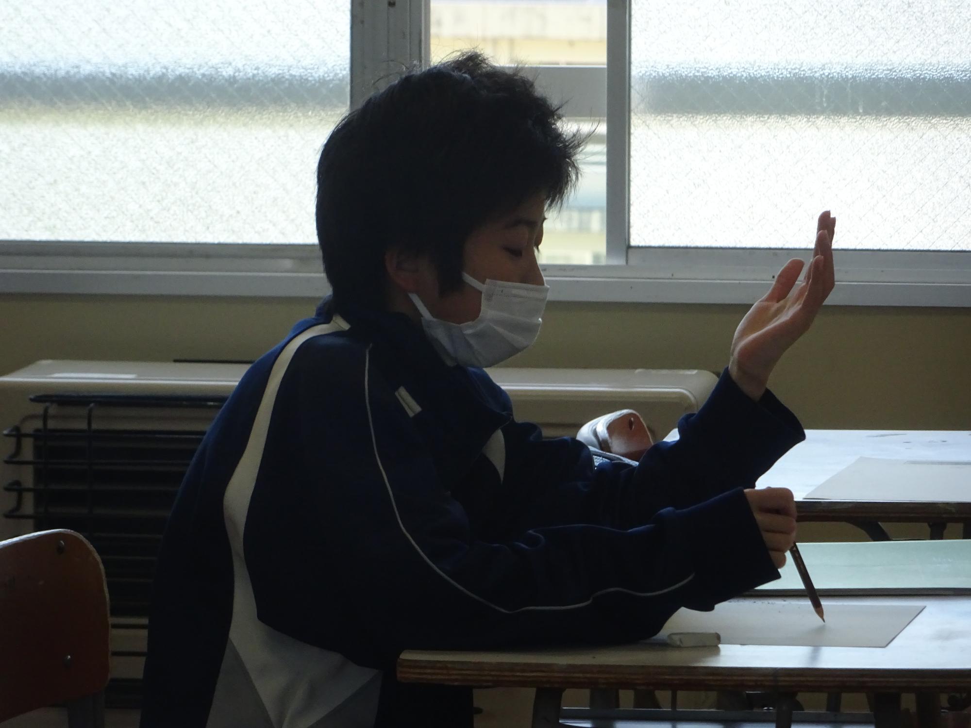 自分手を見つめデッサンする男子生徒