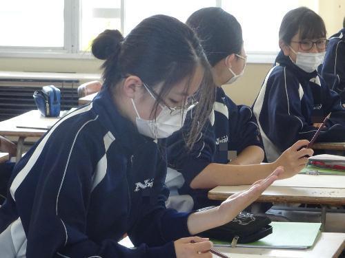 自分手を見つめデッサンする女子生徒