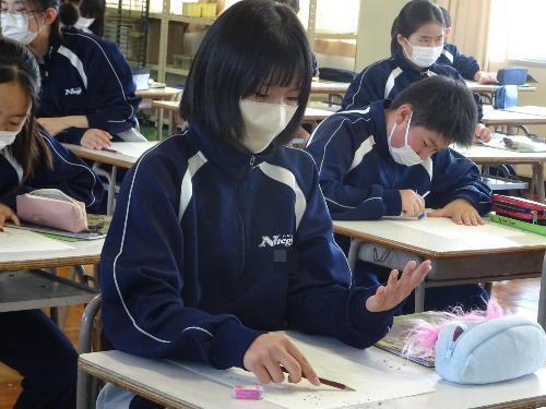 自分手を見つめデッサンする女子生徒