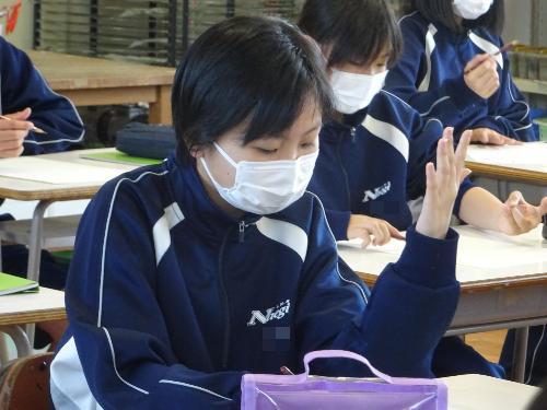 自分手を見つめデッサンする女子生徒
