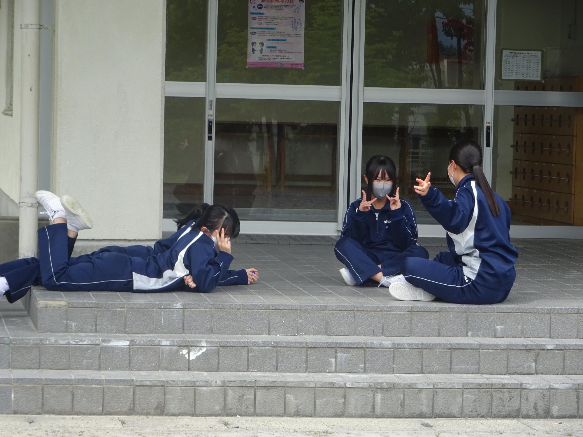 体育館玄関前で寝そべる女子生徒たち