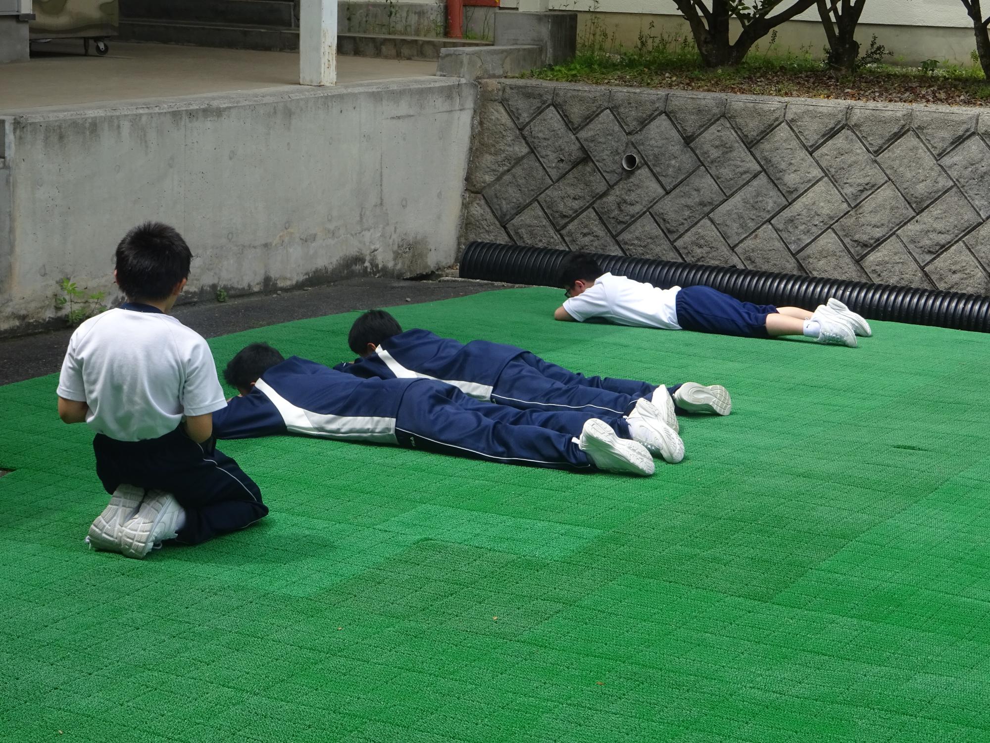 青空パークでうつぶせに寝転ぶ男子生徒たち