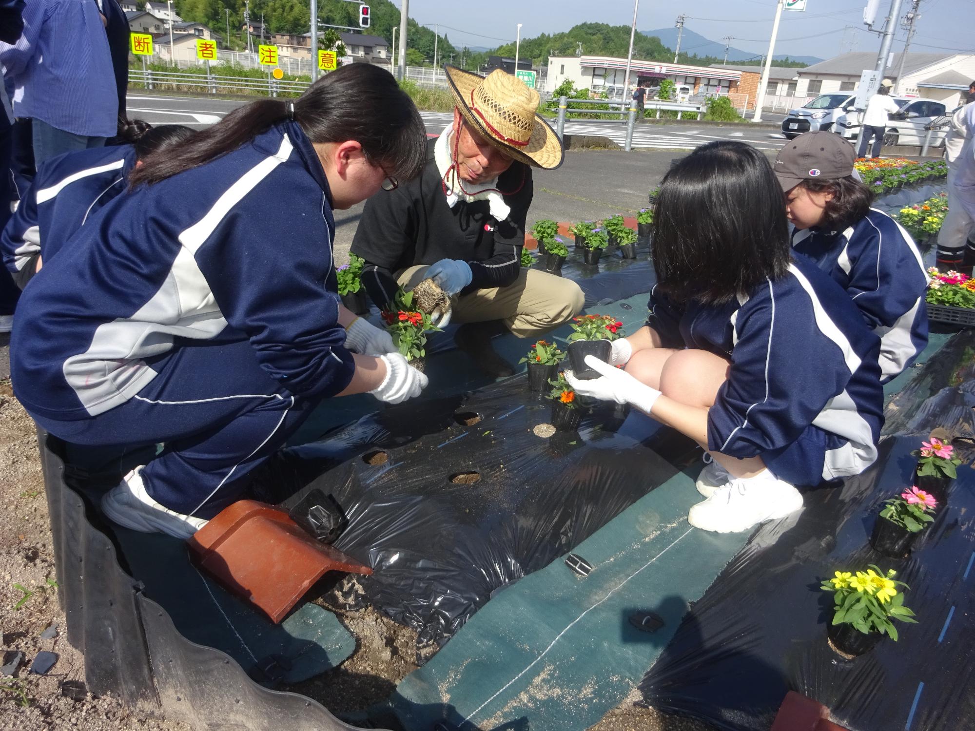 地域の方に教わりながら花を植える生徒