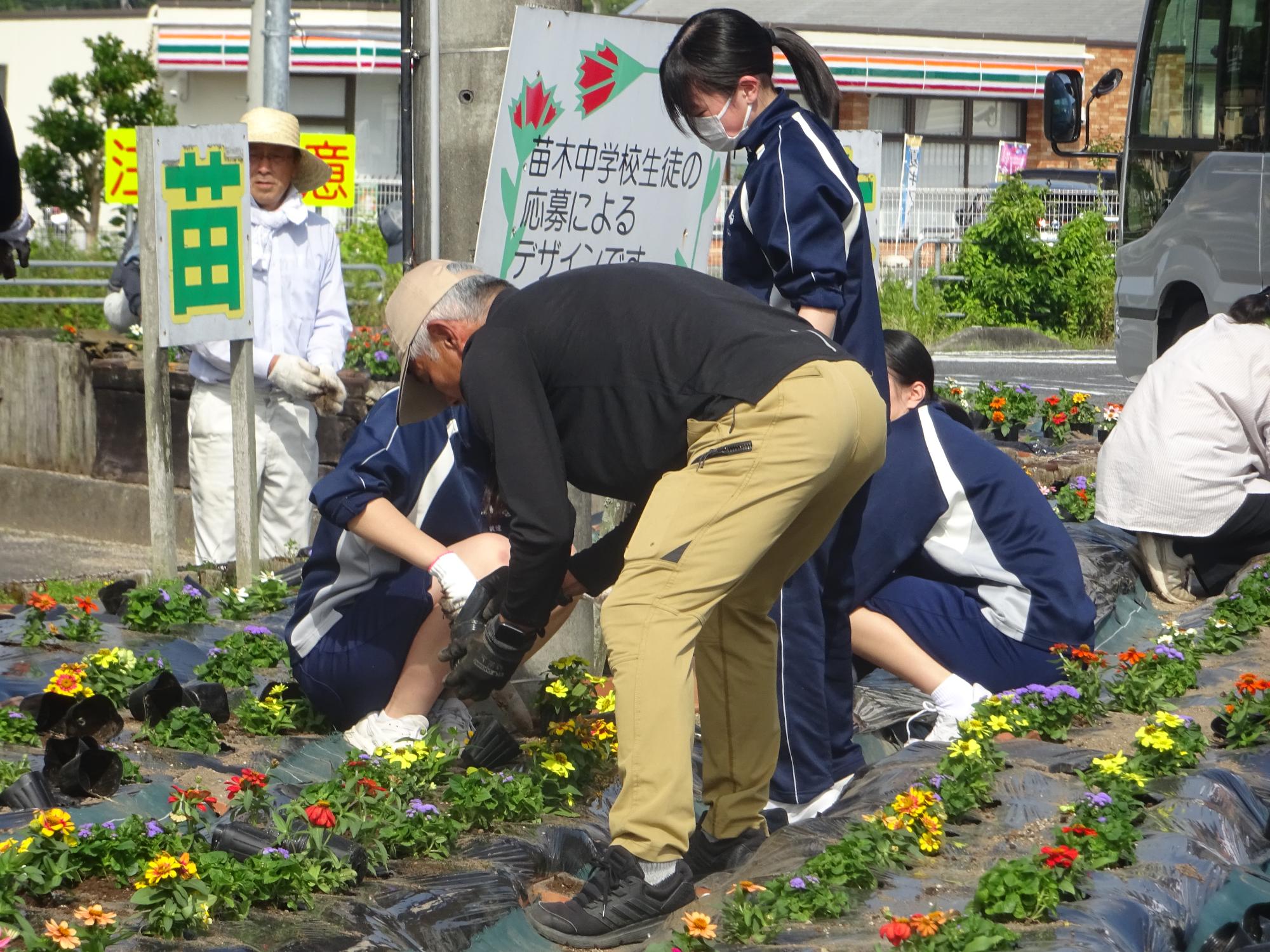 地域の方に教わりながら花を植える生徒