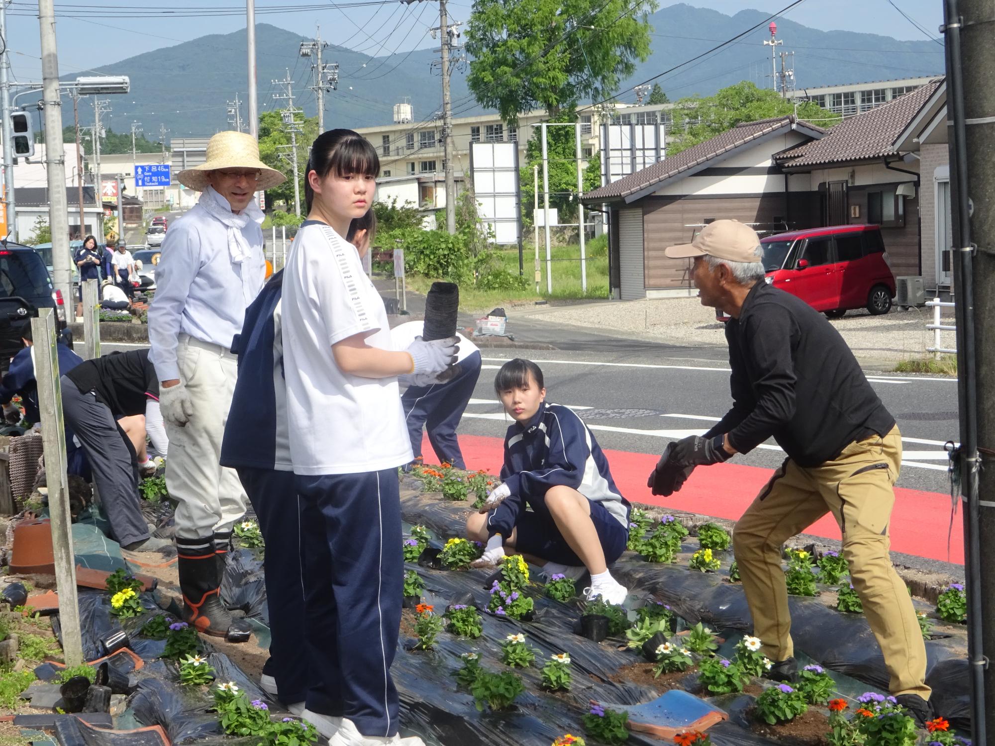 地域の方に教わりながら花を植える生徒