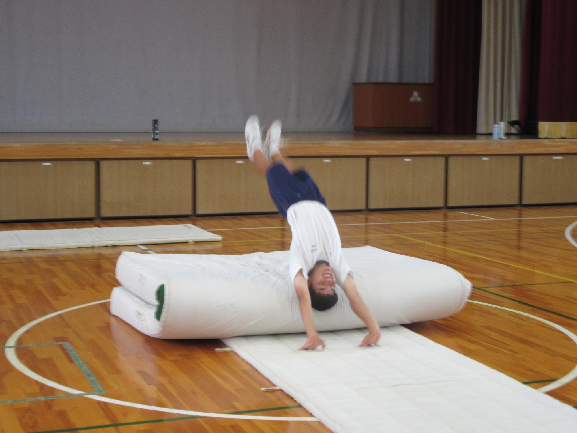 倒立練習でマットに倒れる生徒