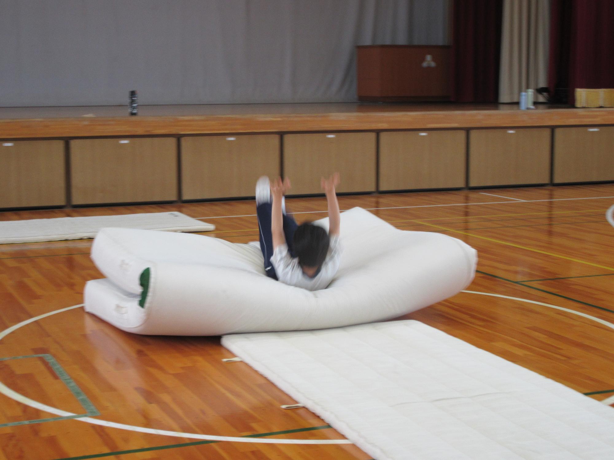 倒立練習でマットに倒れる生徒