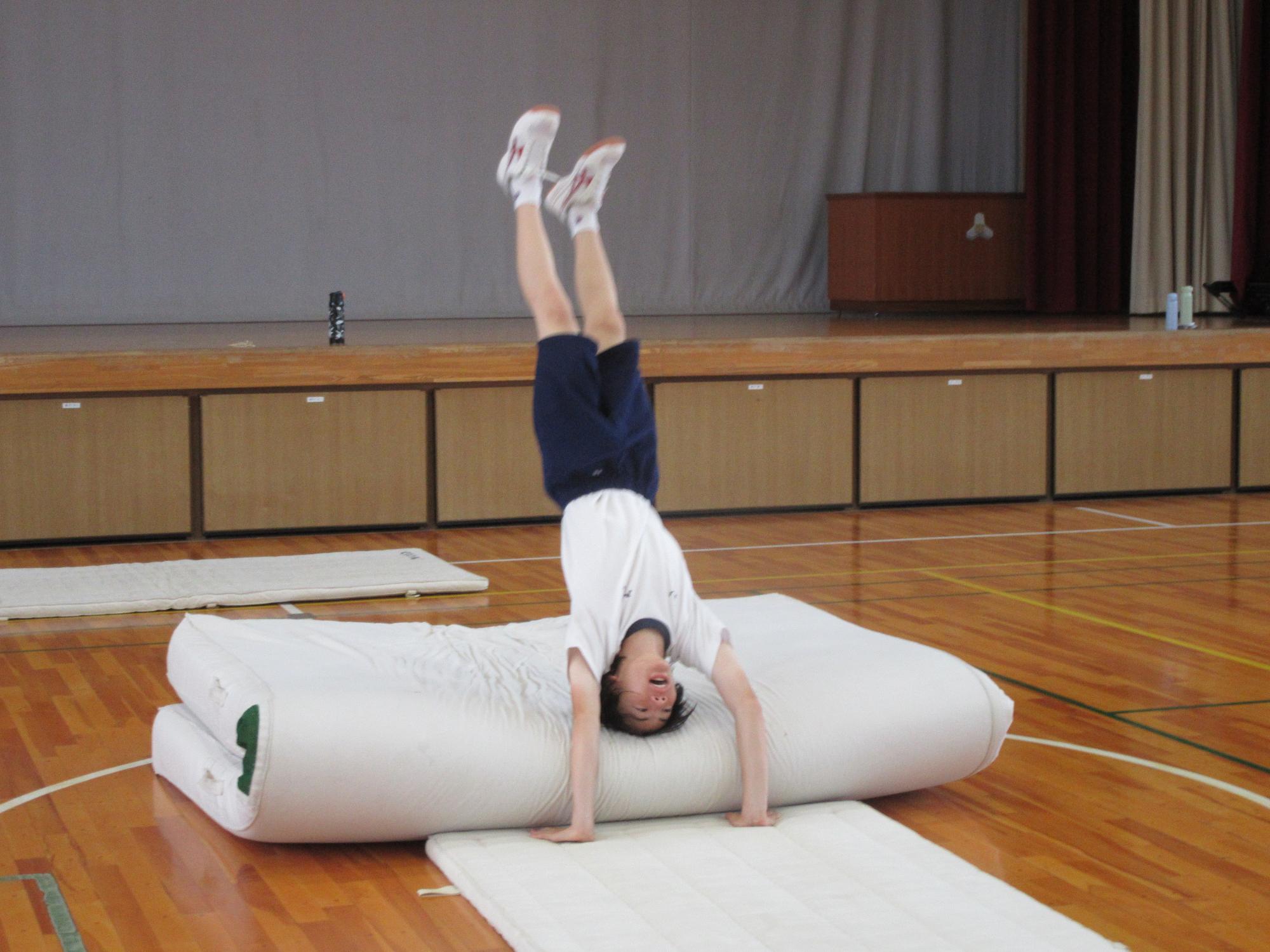 倒立練習でマットに倒れる生徒