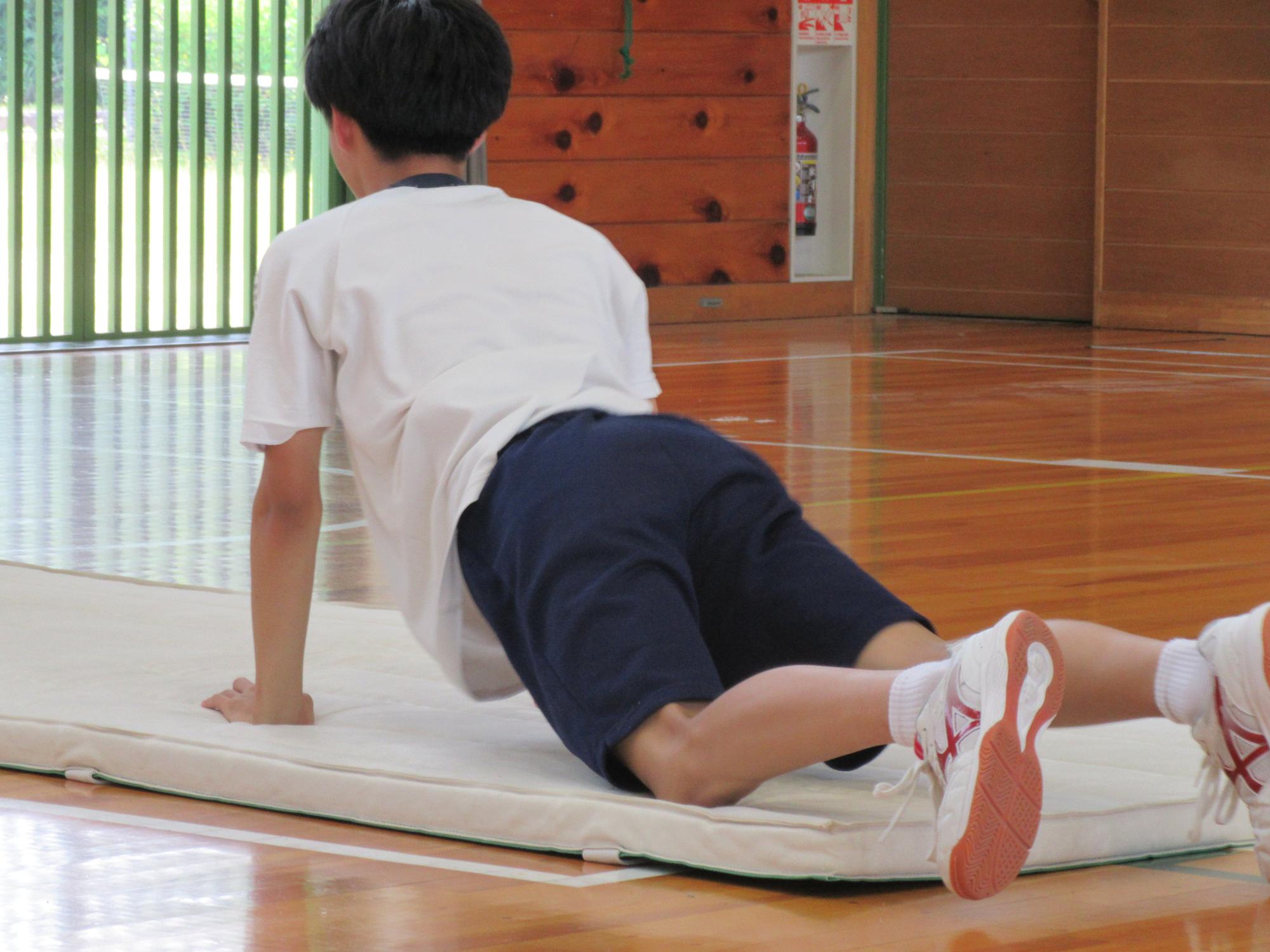 倒立練習でマットに倒れる生徒