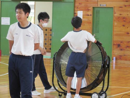 扇風機の前でお腹を出す男子生徒