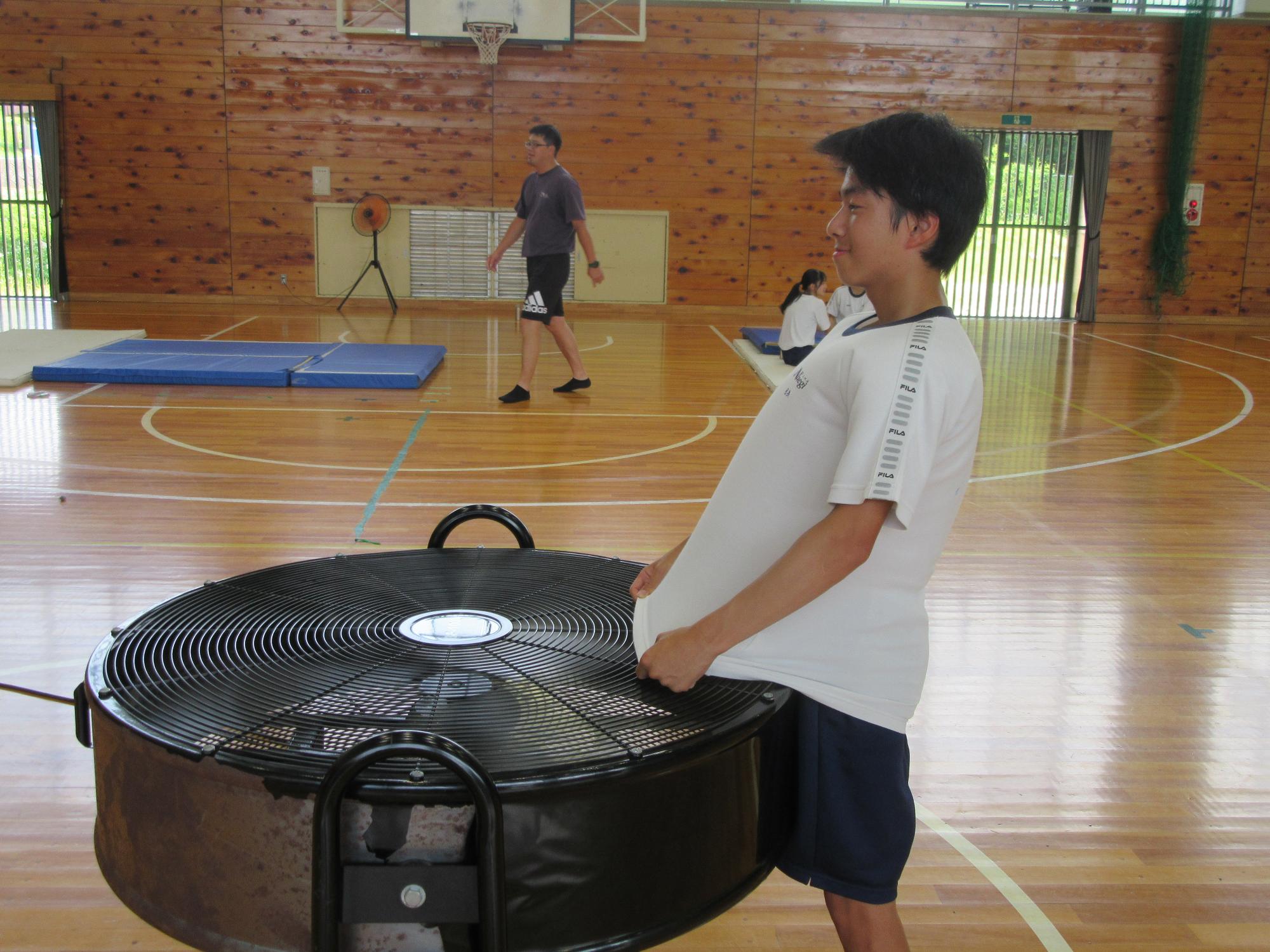 大型扇風機でシャツを乾かす男子生徒