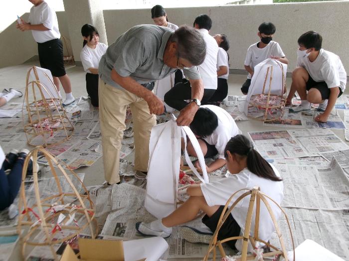 地域の方の指示で笠をつくる中学生