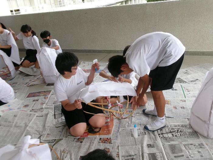 3人で協力して笠をつくる中学生