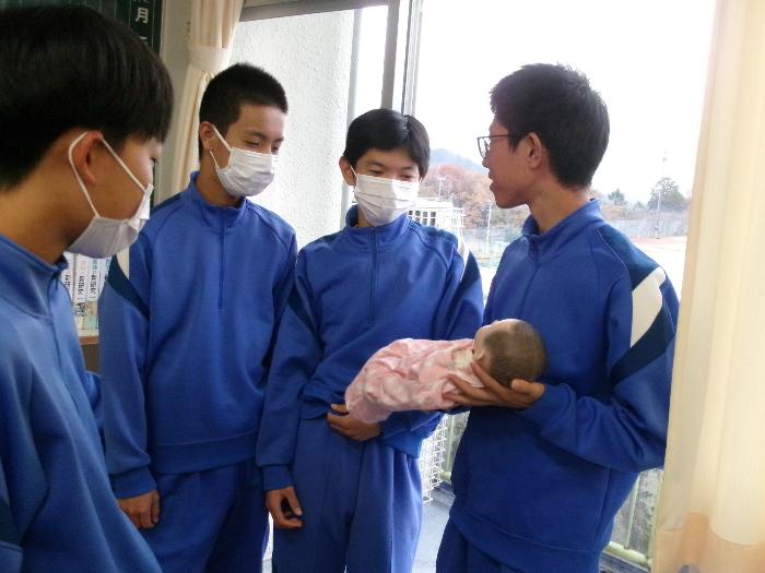 赤ちゃん人形を抱っこする男子生徒