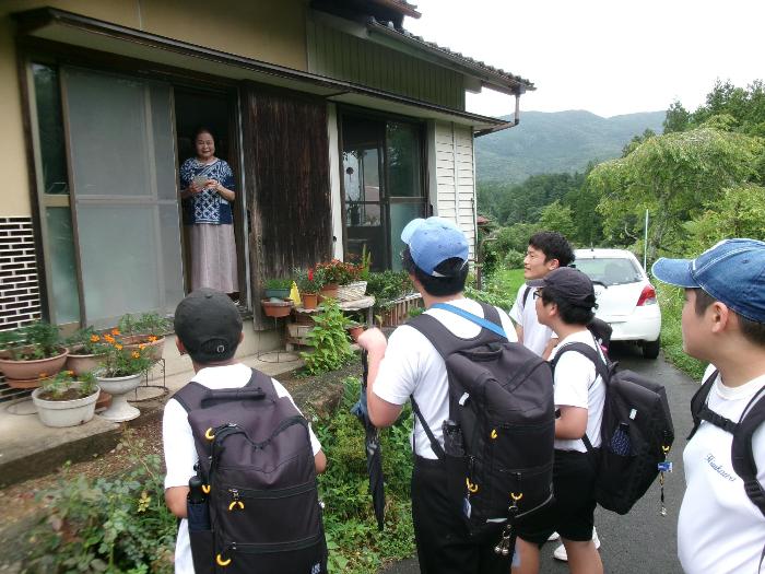 ひとり暮らしの高齢者を訪問し、暑中見舞いはがきを手渡す中学生