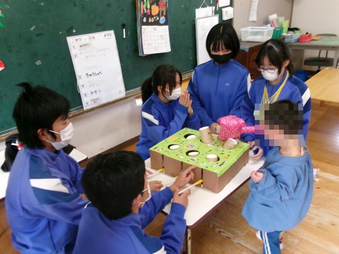 3歳児クラスで手製のもぐらたたきで遊ぶ園児と3年生