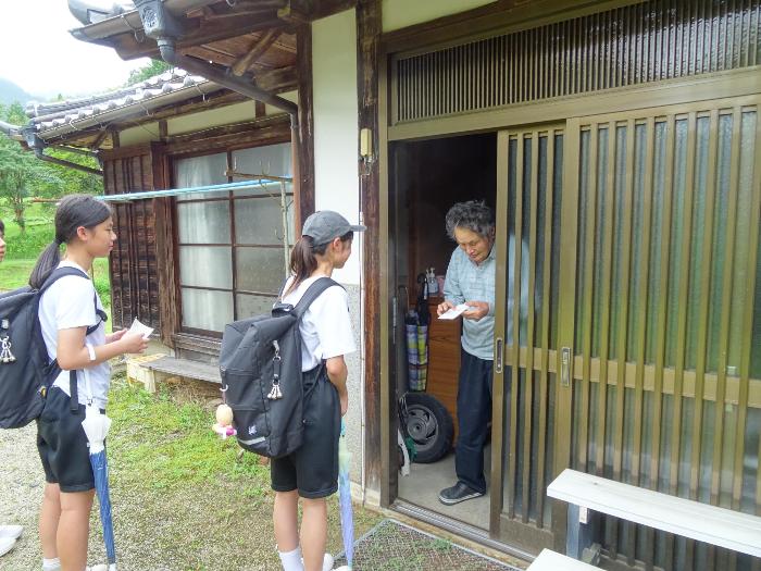 独居老人を訪問し直接暑中見舞いはがきを渡す中学生たち