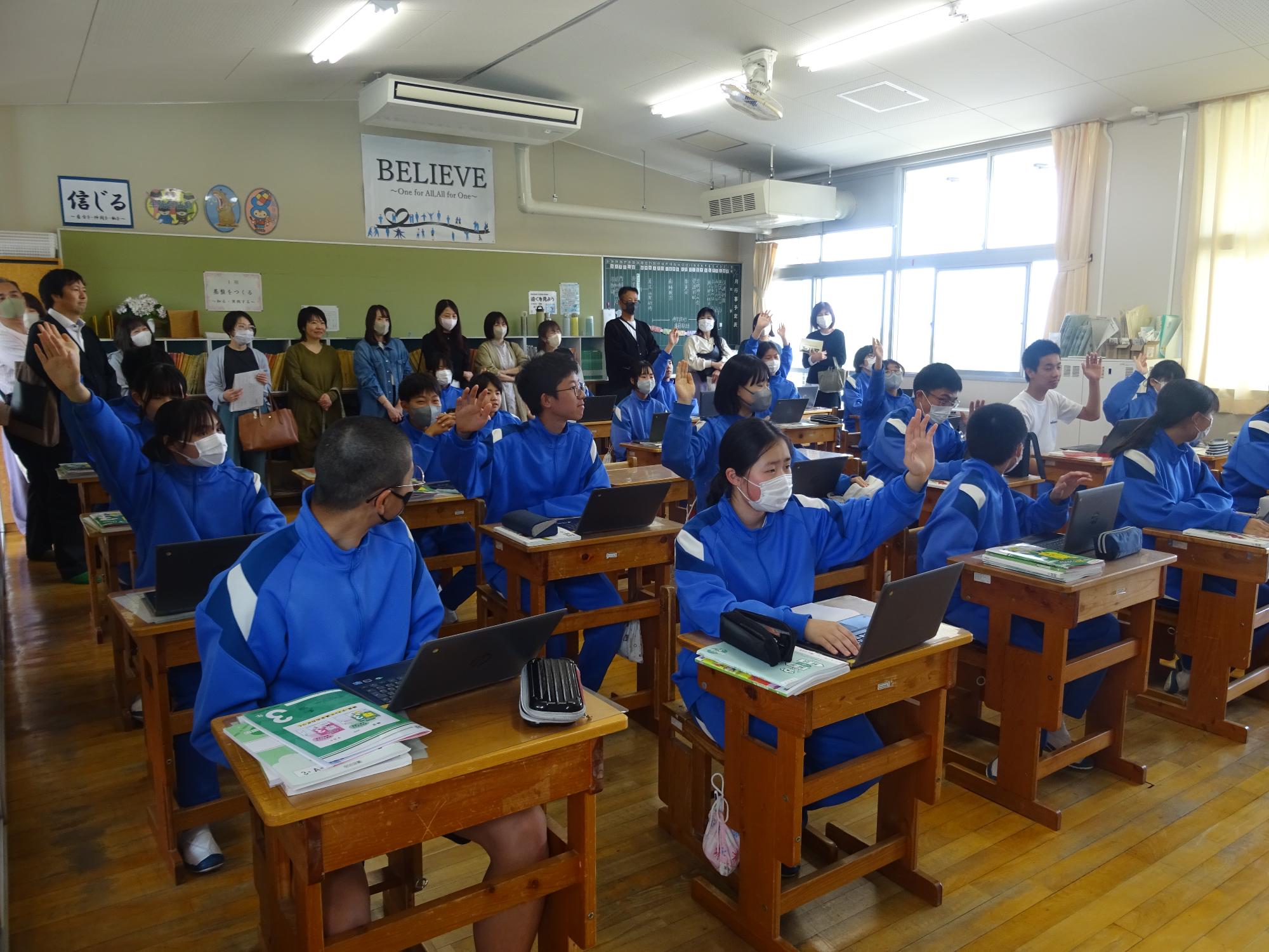 国語の授業の中で挙手して発表しようとする3年生