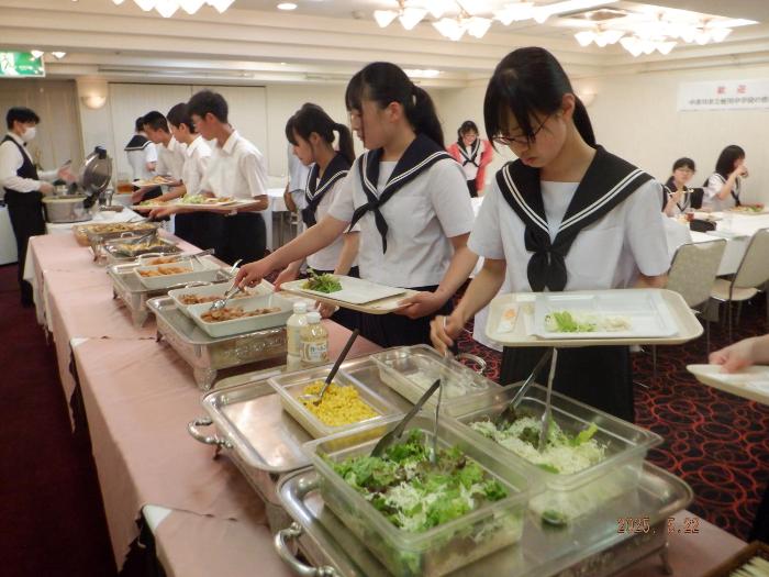 宿泊ホテルでの夕食バイキングで料理を皿にとる3年生