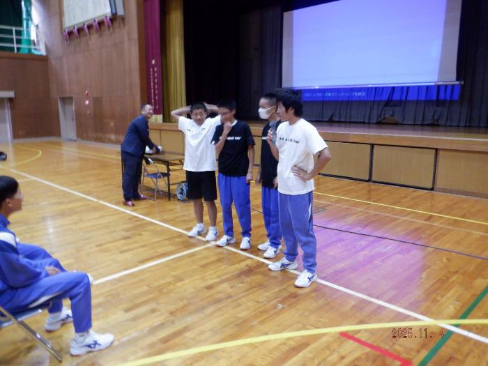 じゃんけんゲームに勝ち、細川さんから会社ユニフォームをもらって着る生徒たち