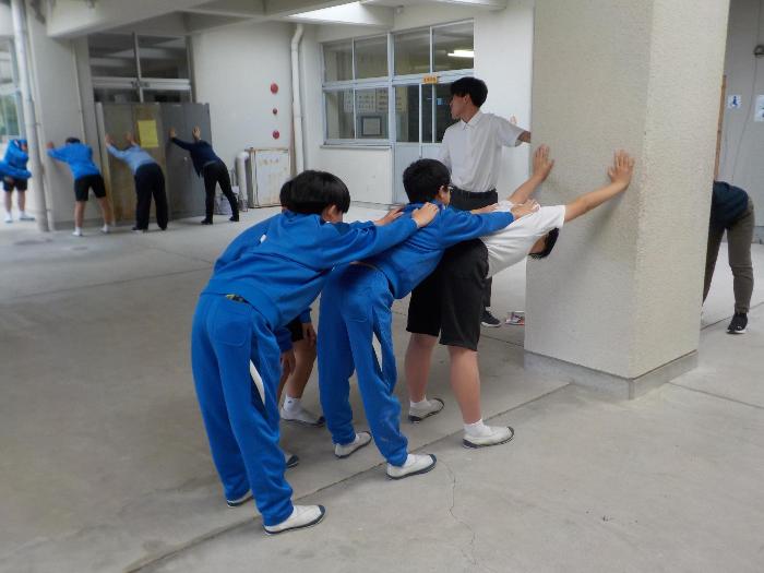 コミュニティホールで背中のストレッチをする生徒たち