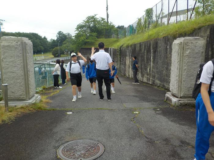 校門で校長とハイタッチをしてあいさつする中学生