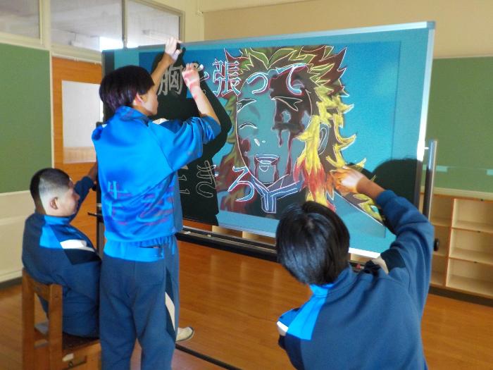 黒板に絵とメッセージを描く2年生