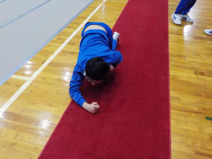 赤絨毯のごみを膝をついてとる2年生