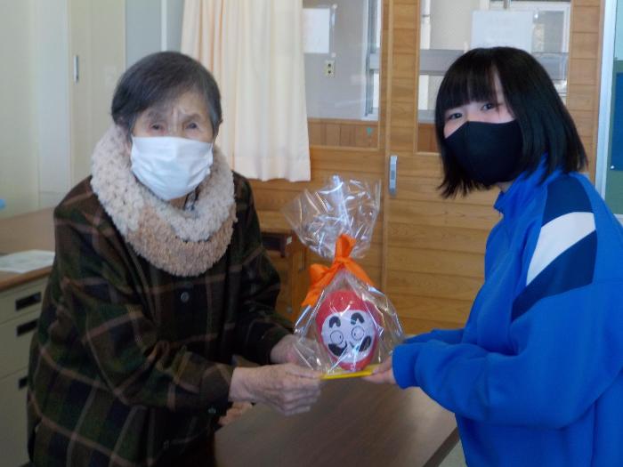 生徒に合格祈願だるまを渡す利用者の方