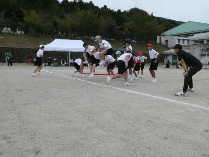 1年学年種目でタイミングを合わせてバーを跳び越える生徒たち