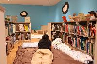 図書館に寝袋を敷いて読み聞かせをする親子