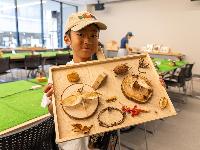 木の実などで作った昆虫標本を持つ男の子