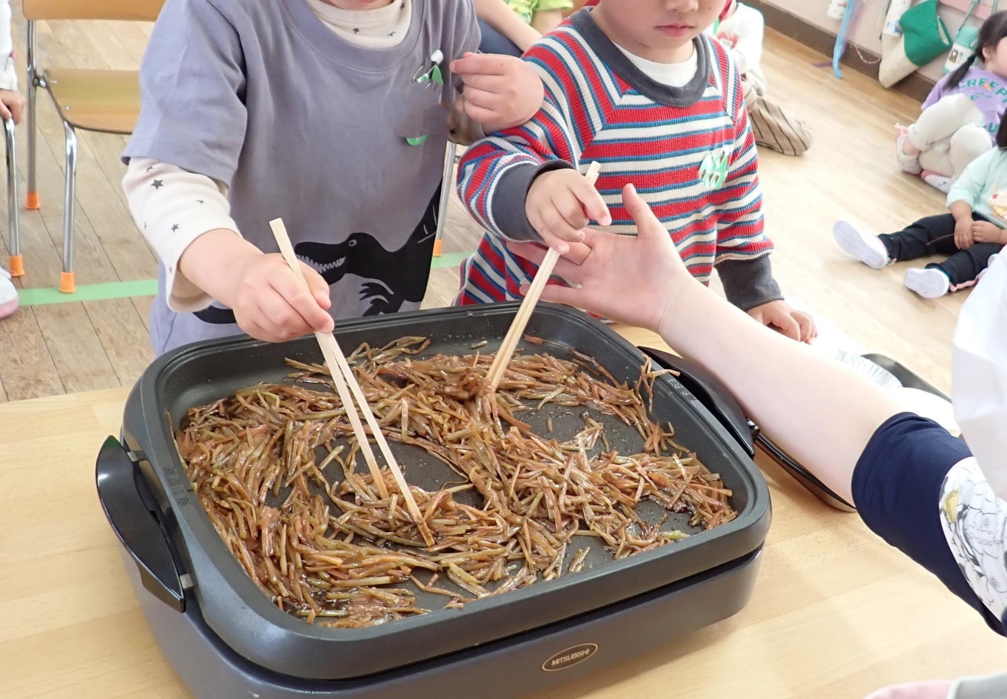 子供がつくしを炒めている