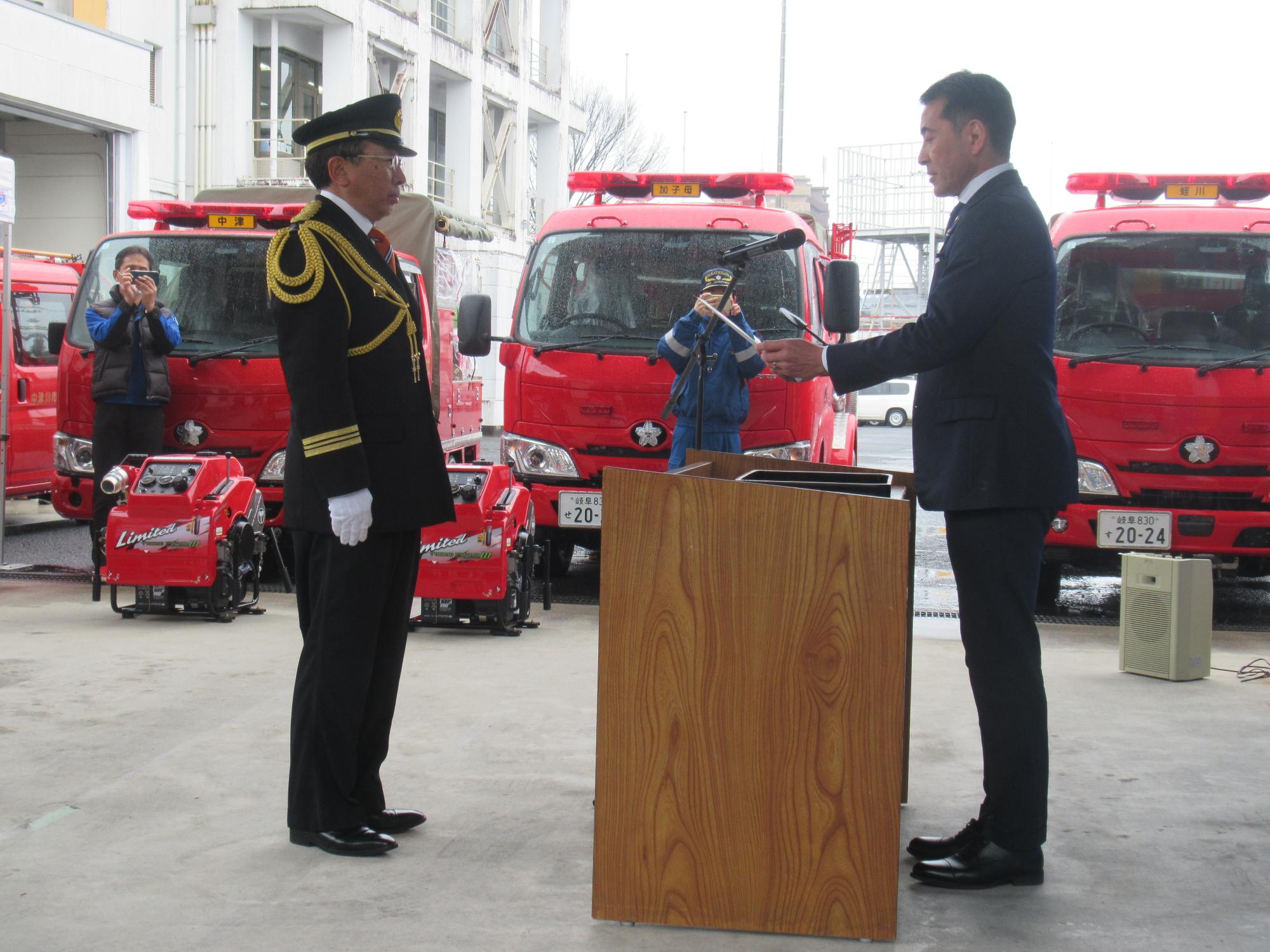 小栗仁志市長から車両の受領を受ける桂川邦俊団長（左）
